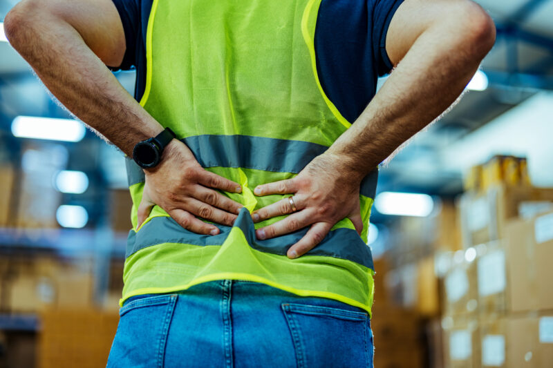 worker holding his back in pain at warehouse.